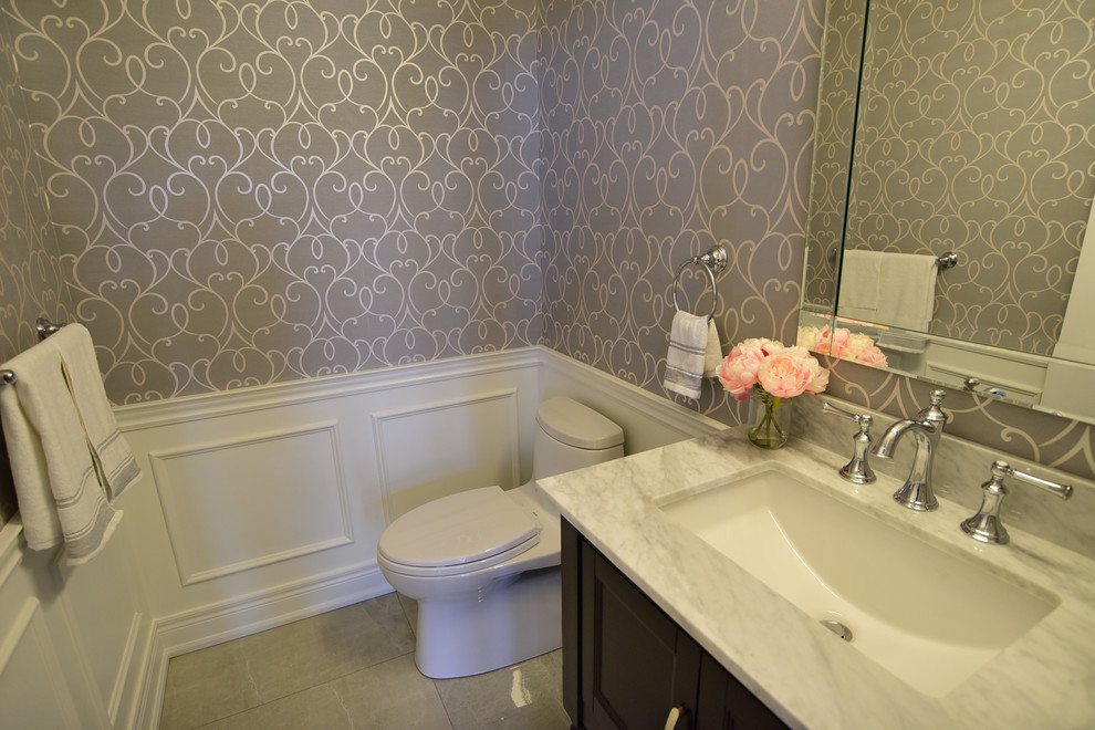 Design ideas for a small transitional powder room in Toronto with recessed-panel cabinets, black cabinets, a one-piece toilet, grey walls, porcelain floors, an undermount sink, marble benchtops, grey floor and white benchtops.