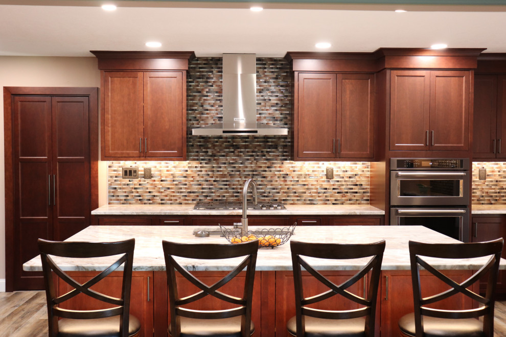 Example of a large transitional l-shaped enclosed kitchen design with an undermount sink, beaded inset cabinets, granite countertops, multicolored backsplash, an island and beige countertops