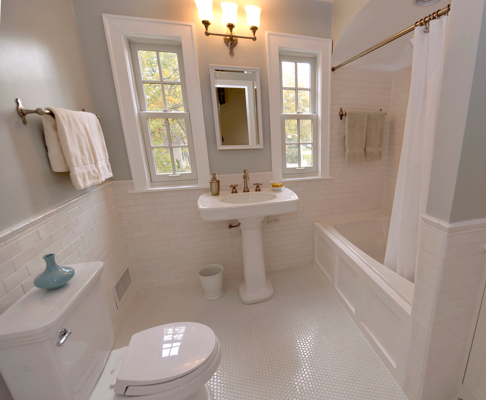 Photo of a mid-sized traditional master bathroom in Chicago with shaker cabinets, white cabinets, a drop-in tub, a shower/bathtub combo, a two-piece toilet, white tile, subway tile, blue walls, ceramic floors, a pedestal sink and marble benchtops.