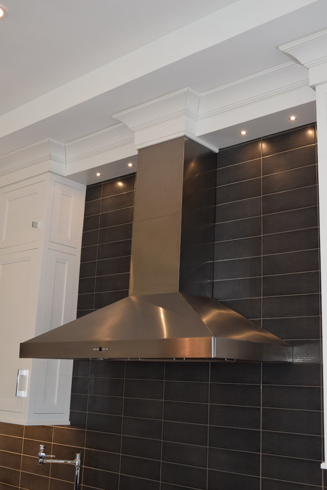 Large transitional l-shaped light wood floor and multicolored floor eat-in kitchen photo in Chicago with beaded inset cabinets, white cabinets, quartz countertops, black backsplash, ceramic backsplash, stainless steel appliances and an island