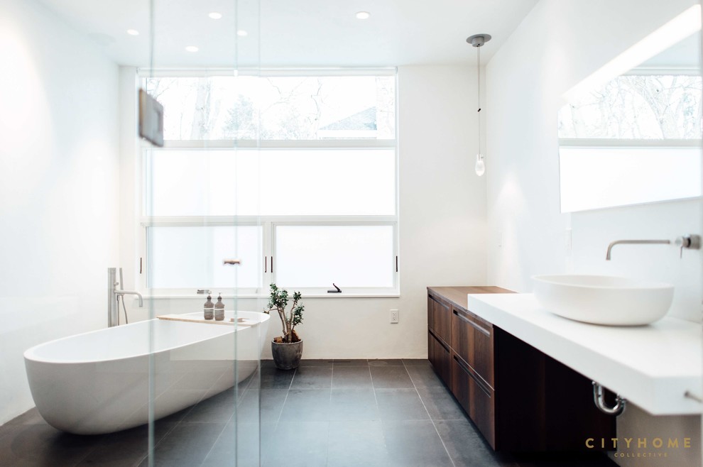 This is an example of a modern master bathroom in Salt Lake City with flat-panel cabinets, dark wood cabinets, a freestanding tub, gray tile and a vessel sink.