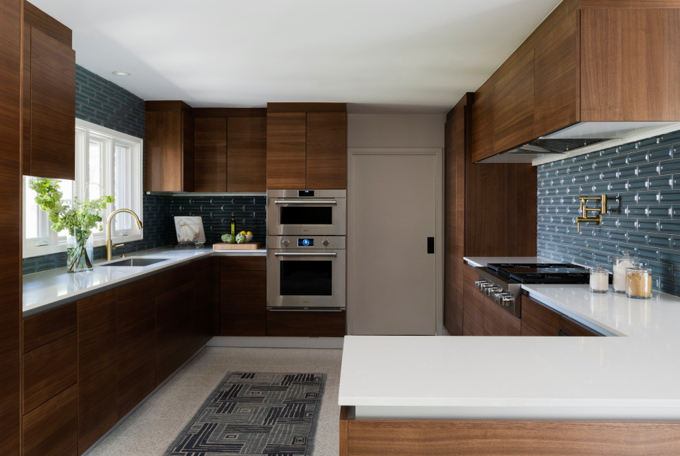 Inspiration for a mid-sized midcentury u-shaped kitchen in Houston with dark wood cabinets, blue splashback, a single-bowl sink, flat-panel cabinets, stainless steel appliances, a peninsula, grey floor and white benchtop.