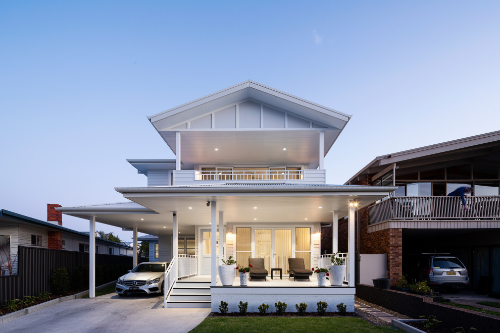 This is an example of a large beach style two-storey white house exterior in Sydney with concrete fiberboard siding, a gable roof, a metal roof, a white roof and board and batten siding.