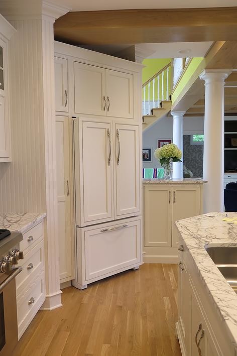 Mid-sized elegant l-shaped light wood floor eat-in kitchen photo with an undermount sink, shaker cabinets, white cabinets, marble countertops, white backsplash, stone tile backsplash, stainless steel appliances and an island