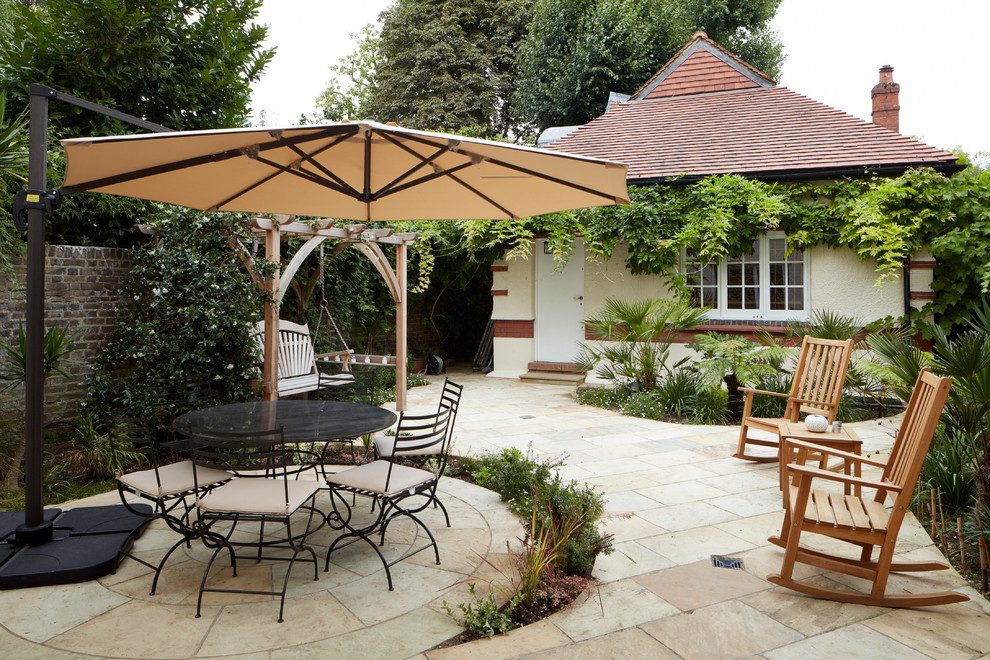 Inspiration for a mediterranean backyard patio in London with natural stone pavers.