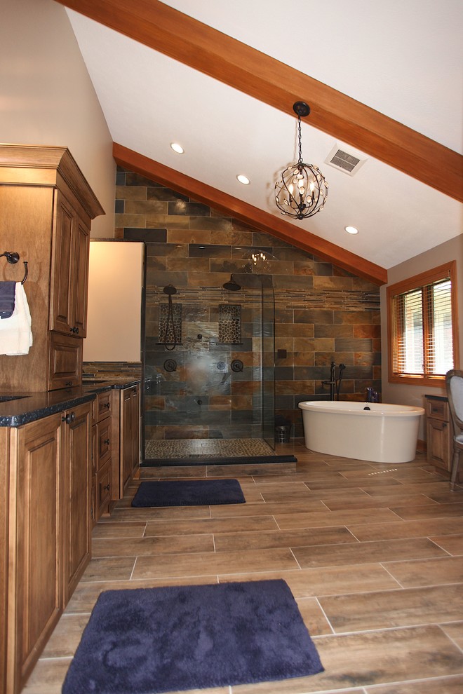 Freestanding bathtub - large rustic master slate tile brown floor freestanding bathtub idea in Indianapolis with brown cabinets, beige walls and an undermount sink
