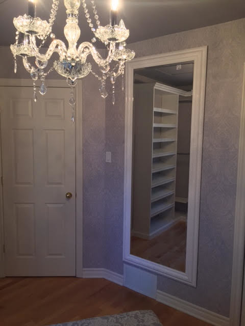 This is an example of a mid-sized traditional women's dressing room in Montreal with open cabinets, white cabinets and medium hardwood floors.