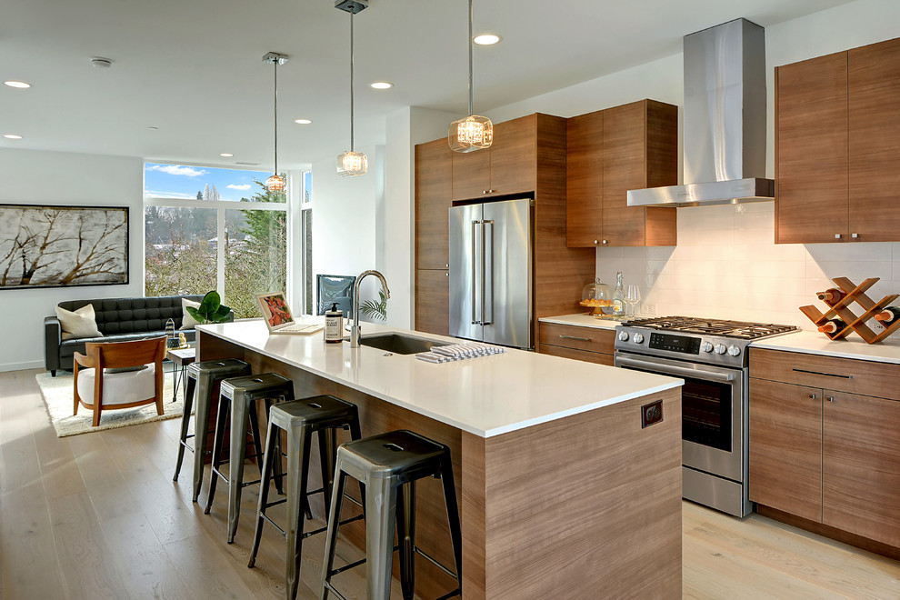 Inspiration for a contemporary galley kitchen in Seattle with an undermount sink, flat-panel cabinets, medium wood cabinets, white splashback, stainless steel appliances, light hardwood floors, with island and beige floor.