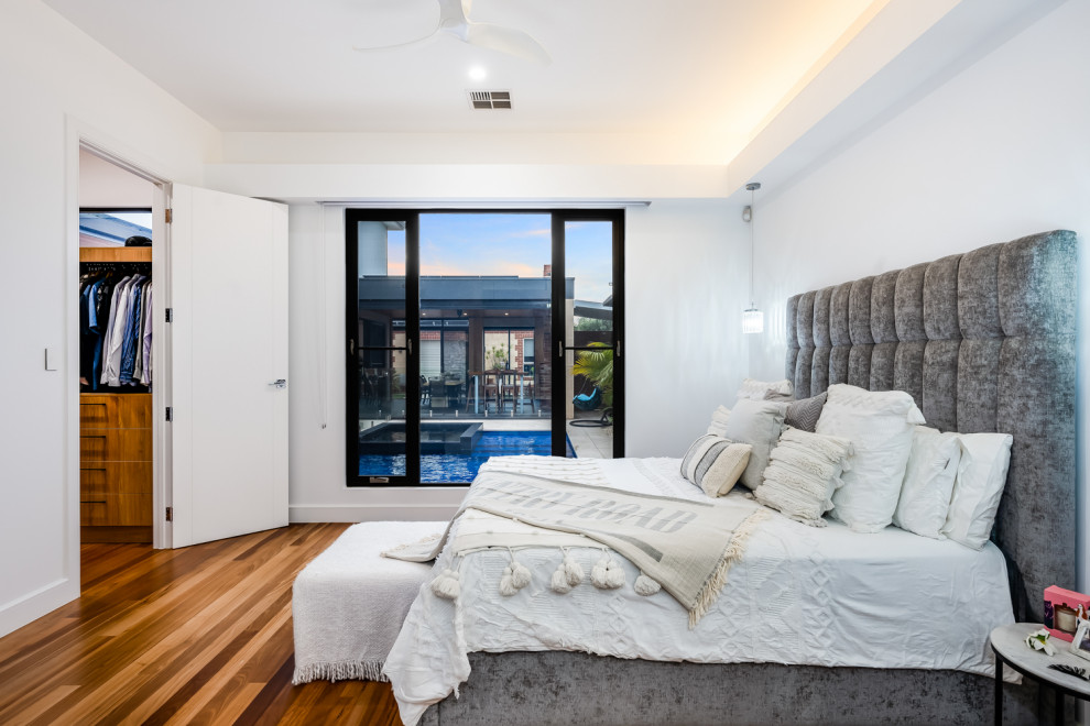Mittelgroßes Modernes Hauptschlafzimmer ohne Kamin mit weißer Wandfarbe, braunem Holzboden und beigem Boden in Adelaide