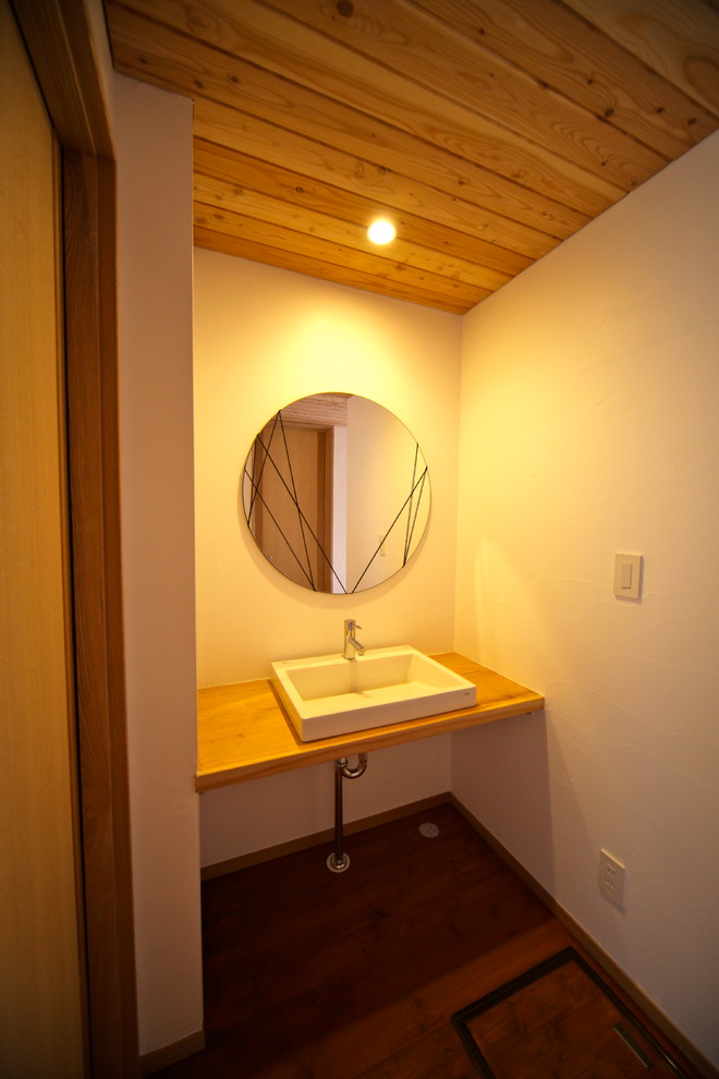 Photo of a small scandinavian powder room in Other with white walls, medium hardwood floors, a drop-in sink, wood benchtops, brown floor and beige benchtops.