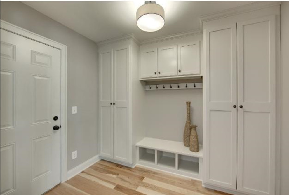 Photo of a mid-sized transitional mudroom in Minneapolis with grey walls, light hardwood floors, a single front door, a white front door and brown floor.