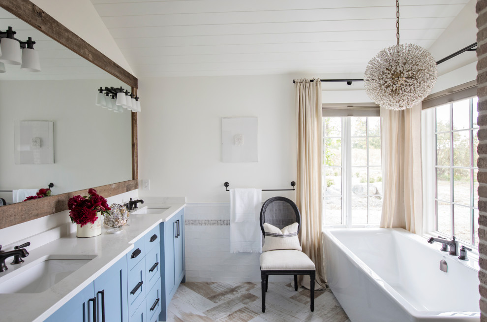 Inspiration for a country bathroom in Other with blue cabinets, a freestanding tub, a double vanity, a built-in vanity, brick walls, shaker cabinets, white tile, white walls, an undermount sink, beige floor, white benchtops, timber and vaulted.