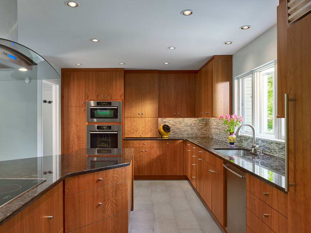This is an example of a mid-sized transitional u-shaped kitchen in Philadelphia with an undermount sink, flat-panel cabinets, medium wood cabinets, granite benchtops, multi-coloured splashback, matchstick tile splashback, stainless steel appliances, porcelain floors and with island.