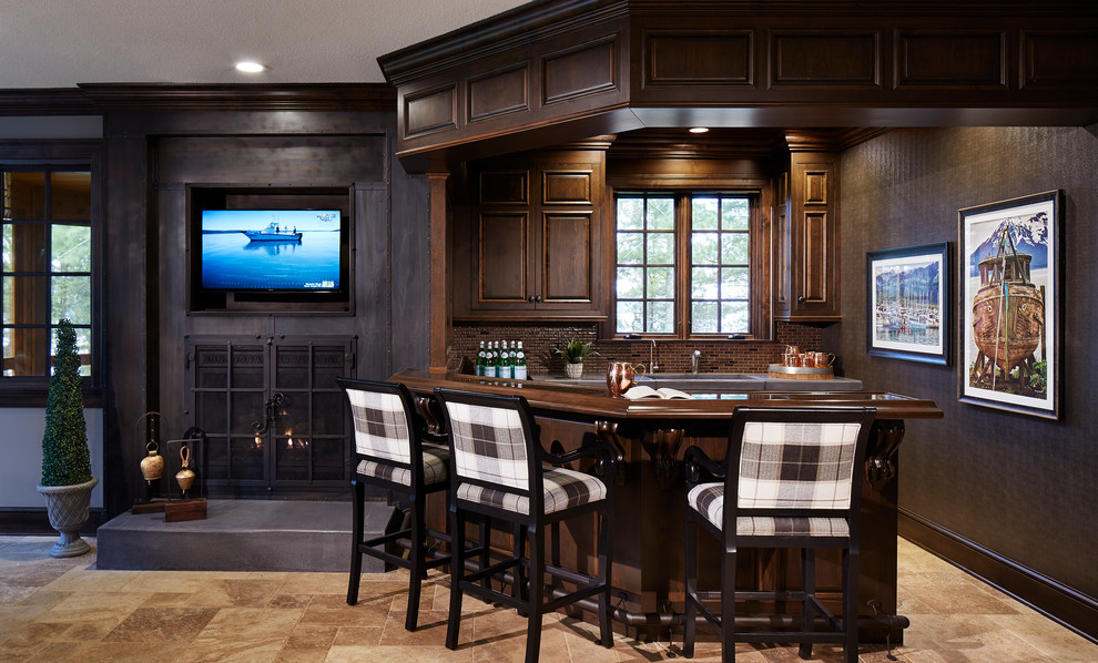 Design ideas for an expansive traditional u-shaped seated home bar in Minneapolis with dark wood cabinets, brown splashback, beige floor, an undermount sink, recessed-panel cabinets, wood benchtops, porcelain splashback, limestone floors and brown benchtop.