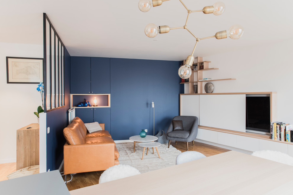 Photo of a mid-sized modern open concept living room in Paris with blue walls, dark hardwood floors, no fireplace, a concealed tv and brown floor.