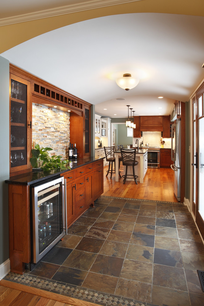 Design ideas for a mid-sized traditional l-shaped eat-in kitchen in Minneapolis with with island, shaker cabinets, medium wood cabinets, granite benchtops, beige splashback, stone tile splashback, stainless steel appliances, an undermount sink and slate floors.