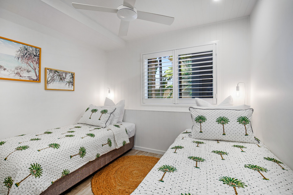 Small beach style guest bedroom in Sunshine Coast with white walls, porcelain floors and grey floor.