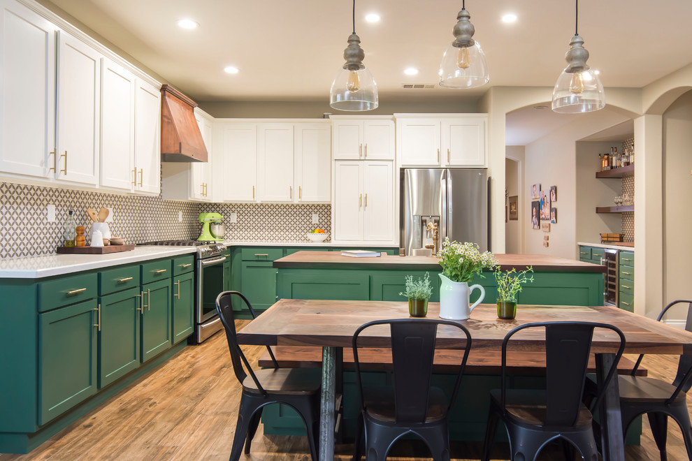 Large transitional l-shaped eat-in kitchen in Los Angeles with a farmhouse sink, shaker cabinets, green cabinets, quartz benchtops, multi-coloured splashback, porcelain splashback, stainless steel appliances, porcelain floors, with island, brown floor and white benchtop.
