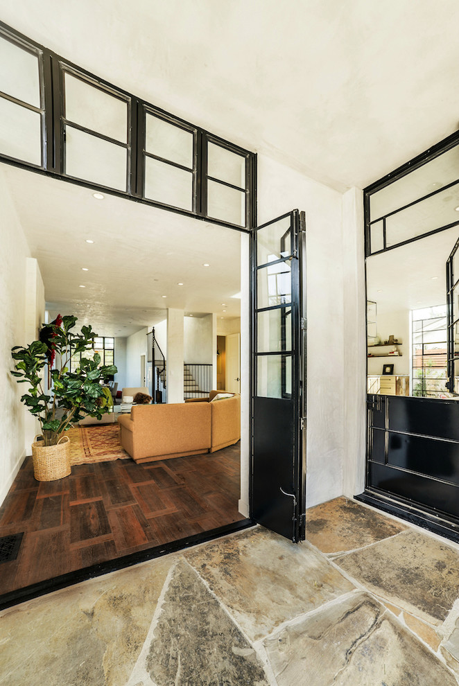 Photo of a large entryway in Los Angeles with white walls, dark hardwood floors and a glass front door.