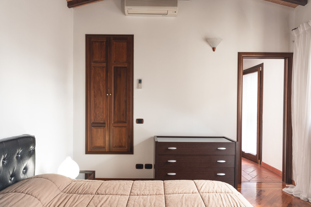 Diseño de dormitorio principal contemporáneo pequeño con paredes blancas, suelo de madera oscura, suelo marrón y vigas vistas