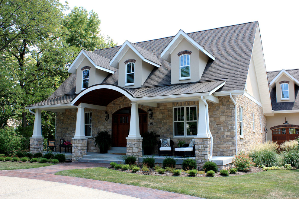 This is an example of a mid-sized traditional two-storey beige house exterior in St Louis with stone veneer, a gable roof and a shingle roof.