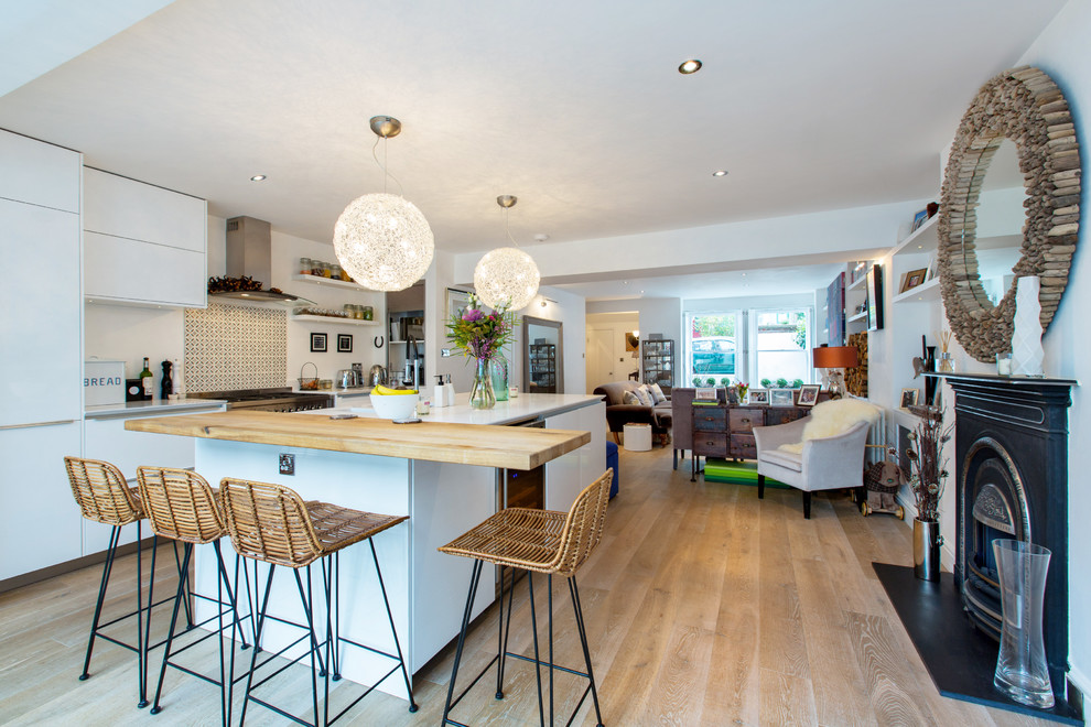 Design ideas for a large contemporary open plan kitchen in London with an integrated sink, white cabinets, multi-coloured splashback and stainless steel appliances.