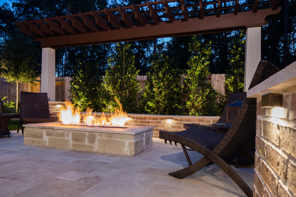 Design ideas for a large traditional backyard patio in Houston with a fire feature, natural stone pavers and a pergola.