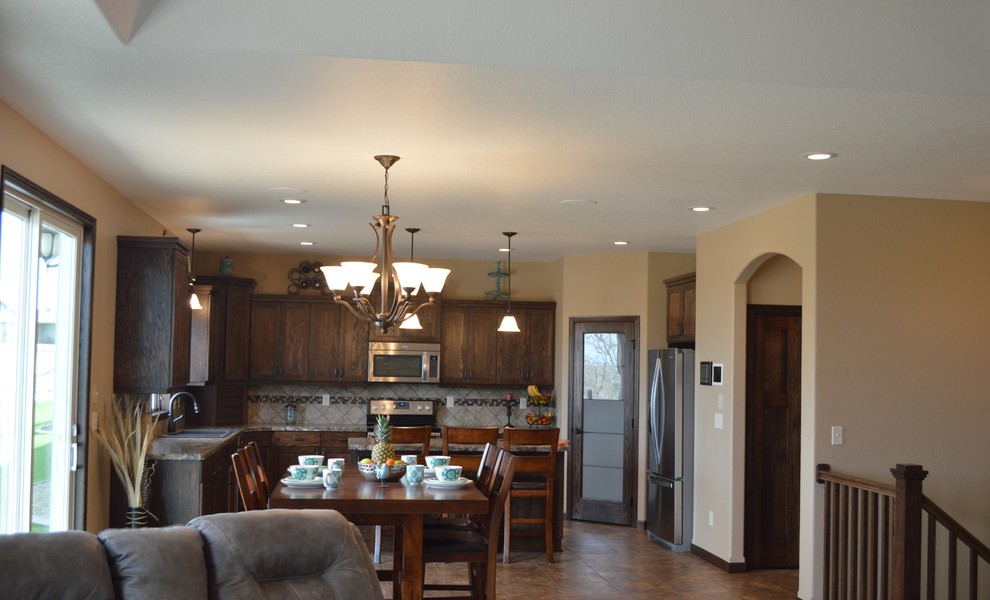 Inspiration for a mid-sized rustic l-shaped laminate floor and beige floor eat-in kitchen remodel with a drop-in sink, recessed-panel cabinets, dark wood cabinets, granite countertops, beige backsplash, stainless steel appliances, an island and ceramic backsplash