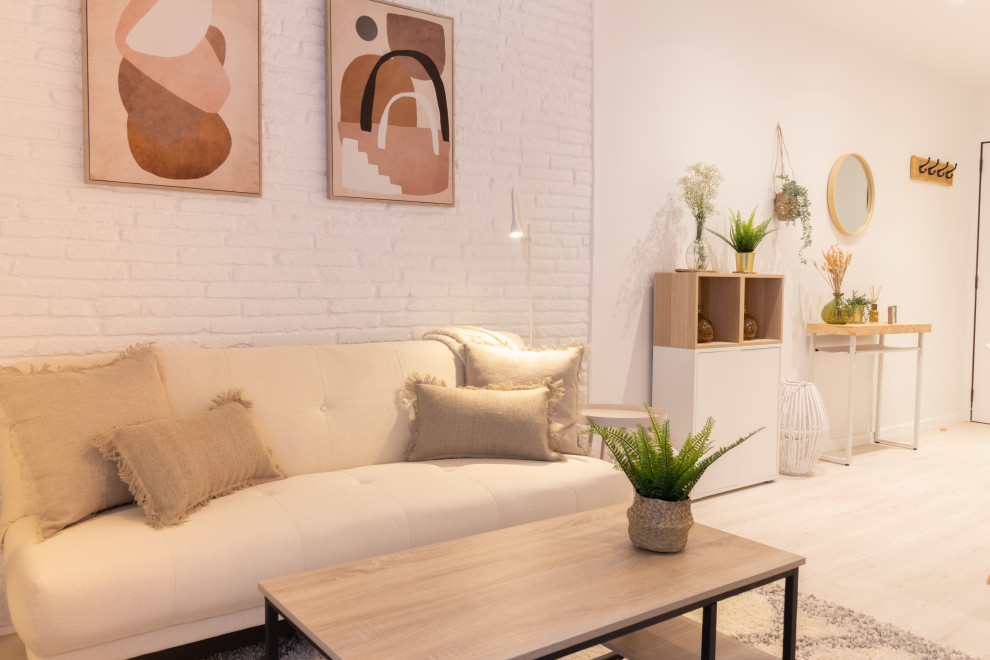 This is an example of a small enclosed living room in Barcelona with white walls, laminate floors, a freestanding tv, beige floors and brick walls.