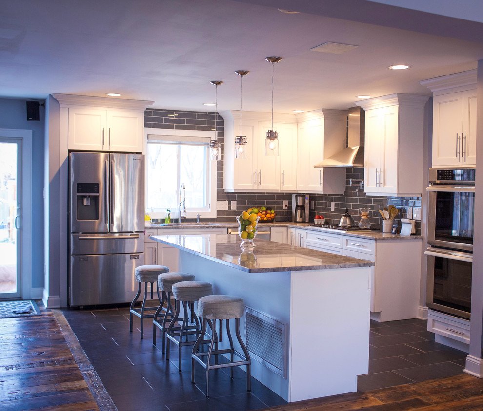 Inspiration for a mid-sized transitional l-shaped porcelain tile and brown floor eat-in kitchen remodel with an undermount sink, recessed-panel cabinets, white cabinets, granite countertops, gray backsplash, porcelain backsplash, stainless steel appliances, an island and gray countertops