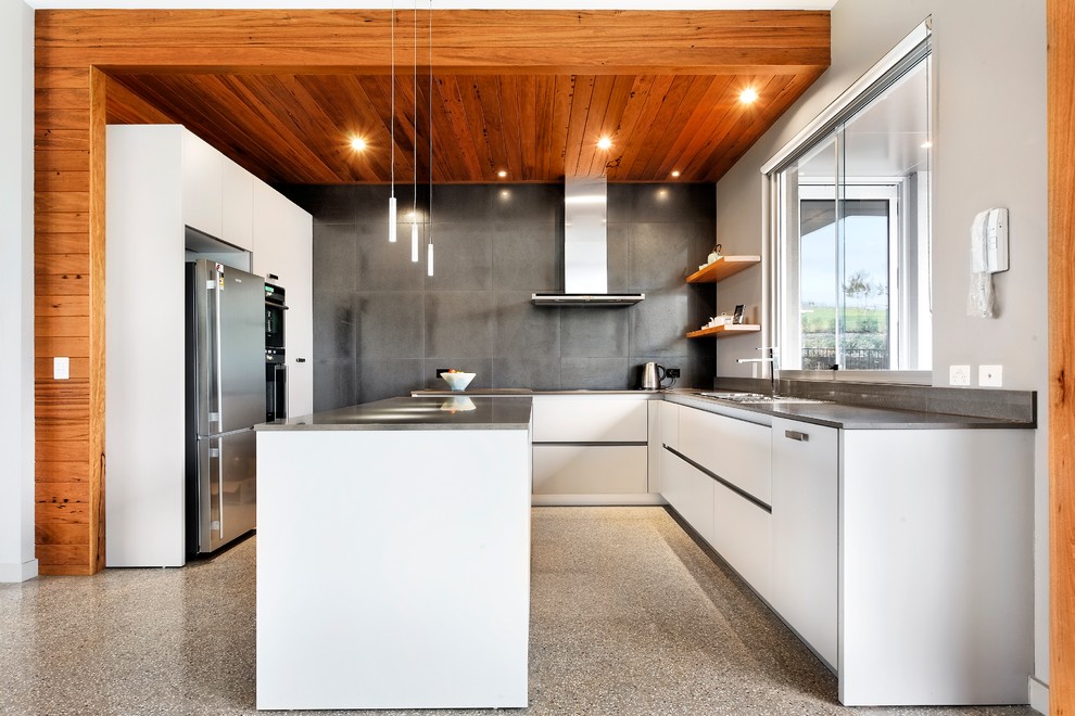 Design ideas for a mid-sized contemporary u-shaped eat-in kitchen in Melbourne with a drop-in sink, flat-panel cabinets, white cabinets, grey splashback, stainless steel appliances, quartz benchtops, porcelain splashback, concrete floors and with island.