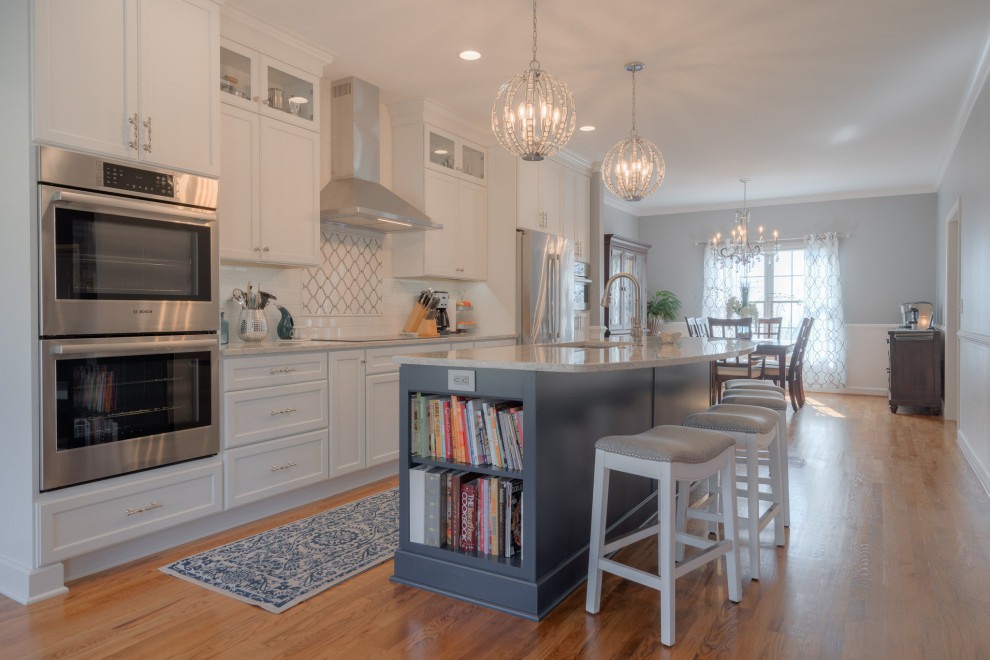 Mid-sized transitional galley medium tone wood floor eat-in kitchen photo with an undermount sink, flat-panel cabinets, white cabinets, quartz countertops, white backsplash, subway tile backsplash, stainless steel appliances, an island and white countertops