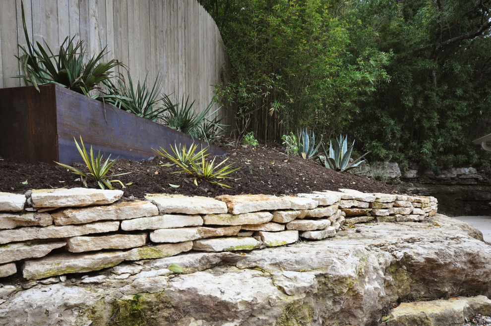 Small modern backyard xeriscape in Austin with natural stone pavers.