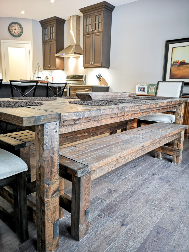 Mid-sized mountain style l-shaped medium tone wood floor and gray floor kitchen/dining room combo photo with a double-bowl sink, recessed-panel cabinets, dark wood cabinets, granite countertops, stainless steel appliances, an island, gray countertops, gray walls and no fireplace