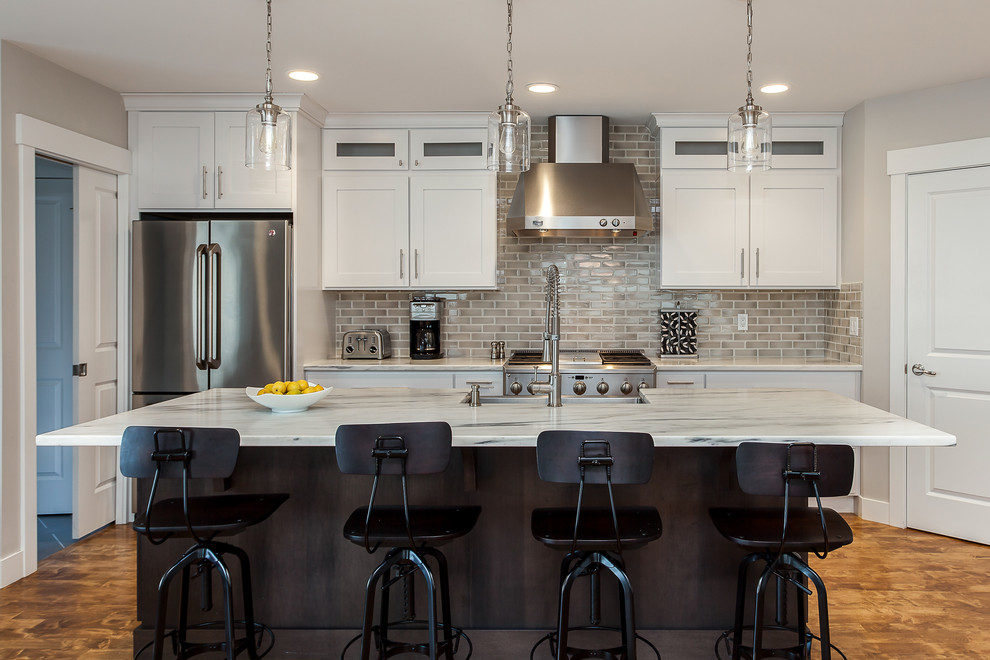 This is an example of a contemporary kitchen in Denver with an undermount sink, shaker cabinets, white cabinets, granite benchtops, beige splashback, subway tile splashback, stainless steel appliances, medium hardwood floors and with island.