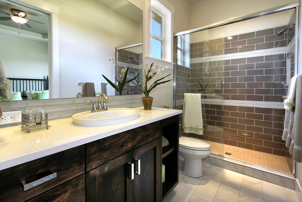 This is an example of a large transitional bathroom in Boise with a drop-in sink, shaker cabinets, dark wood cabinets, engineered quartz benchtops, an open shower, gray tile, porcelain tile and porcelain floors.