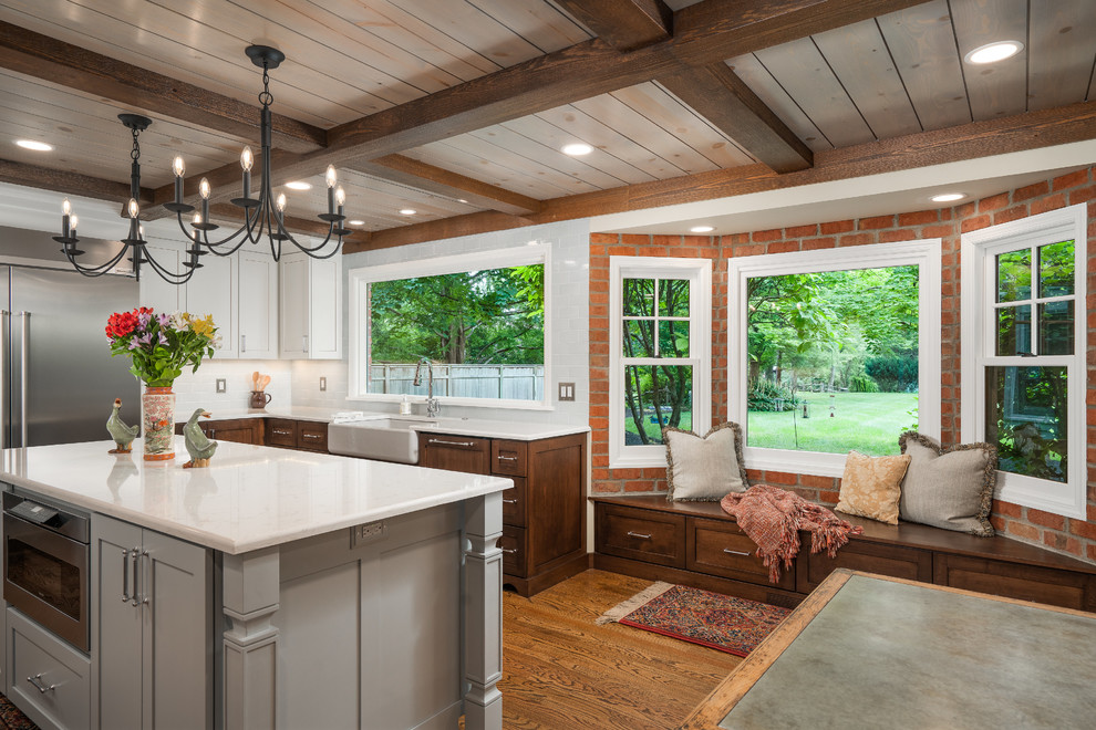 Inspiration for a mid-sized transitional galley medium tone wood floor and brown floor eat-in kitchen remodel in Columbus with a farmhouse sink, shaker cabinets, dark wood cabinets, quartz countertops, white backsplash, subway tile backsplash, stainless steel appliances, an island and white countertops