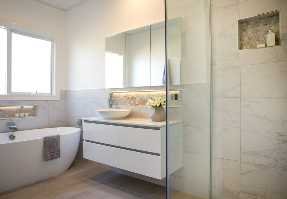 Design ideas for a mid-sized contemporary 3/4 bathroom in Melbourne with raised-panel cabinets, white cabinets, a freestanding tub, a curbless shower, gray tile, porcelain tile, white walls, porcelain floors, a vessel sink and engineered quartz benchtops.