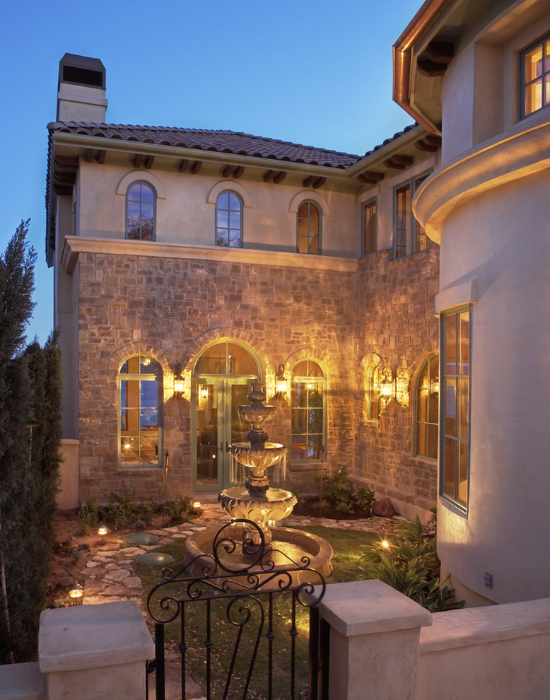 This is an example of a large mediterranean two-storey brown house exterior in Austin with stone veneer, a hip roof and a tile roof.