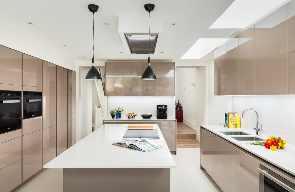 This is an example of a contemporary galley separate kitchen in London with a double-bowl sink, flat-panel cabinets, beige cabinets, white splashback, black appliances and with island.