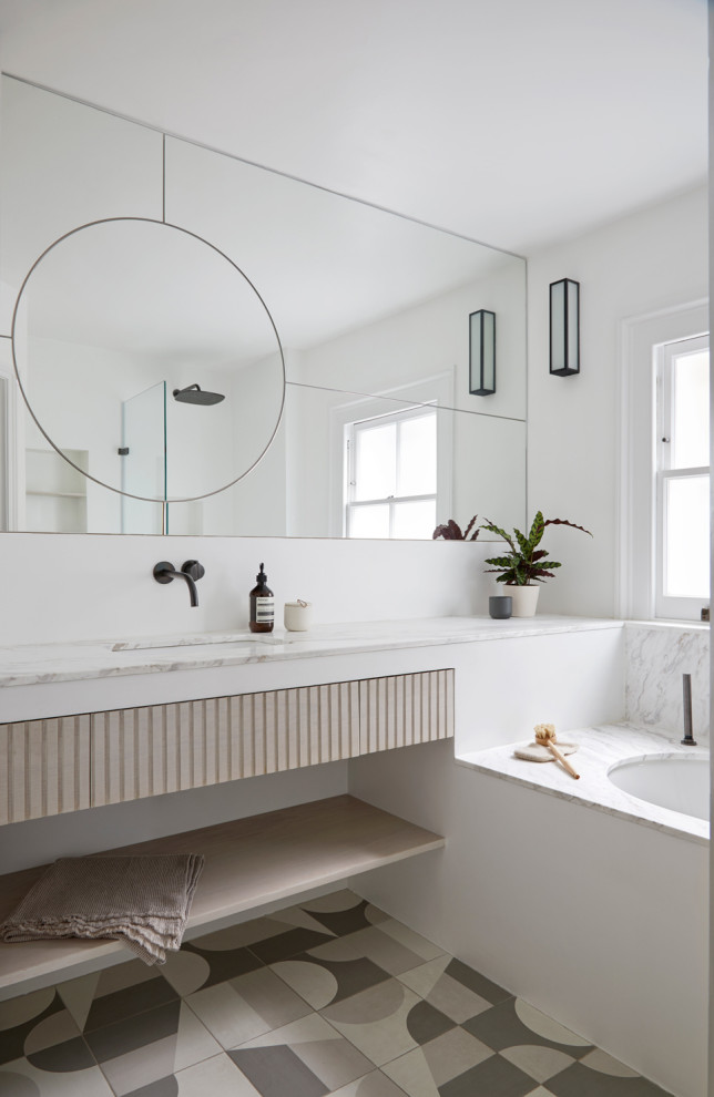 Inspiration for a contemporary bathroom in London with flat-panel cabinets, light wood cabinets, a submerged bath, white walls, a submerged sink, multi-coloured floors, white worktops and a floating vanity unit.