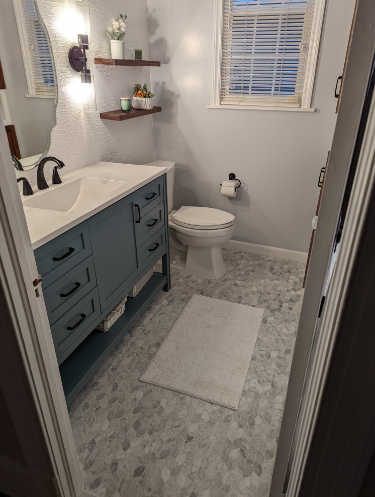 This is an example of a small eclectic bathroom in DC Metro with shaker cabinets, green cabinets, an alcove tub, a shower/bathtub combo, a two-piece toilet, white tile, porcelain tile, grey walls, marble floors, an integrated sink, marble benchtops, grey floor, a shower curtain, white benchtops, a niche, a single vanity, a freestanding vanity, wood and wallpaper.