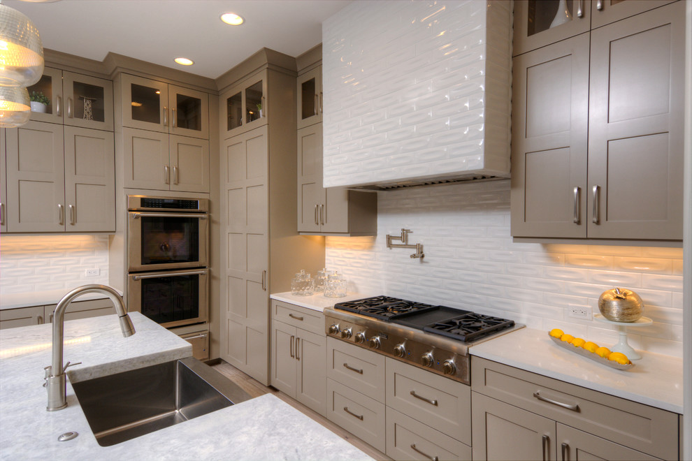 This is an example of a large contemporary kitchen in Denver with white splashback, light hardwood floors, with island, a drop-in sink, shaker cabinets, grey cabinets and stainless steel appliances.