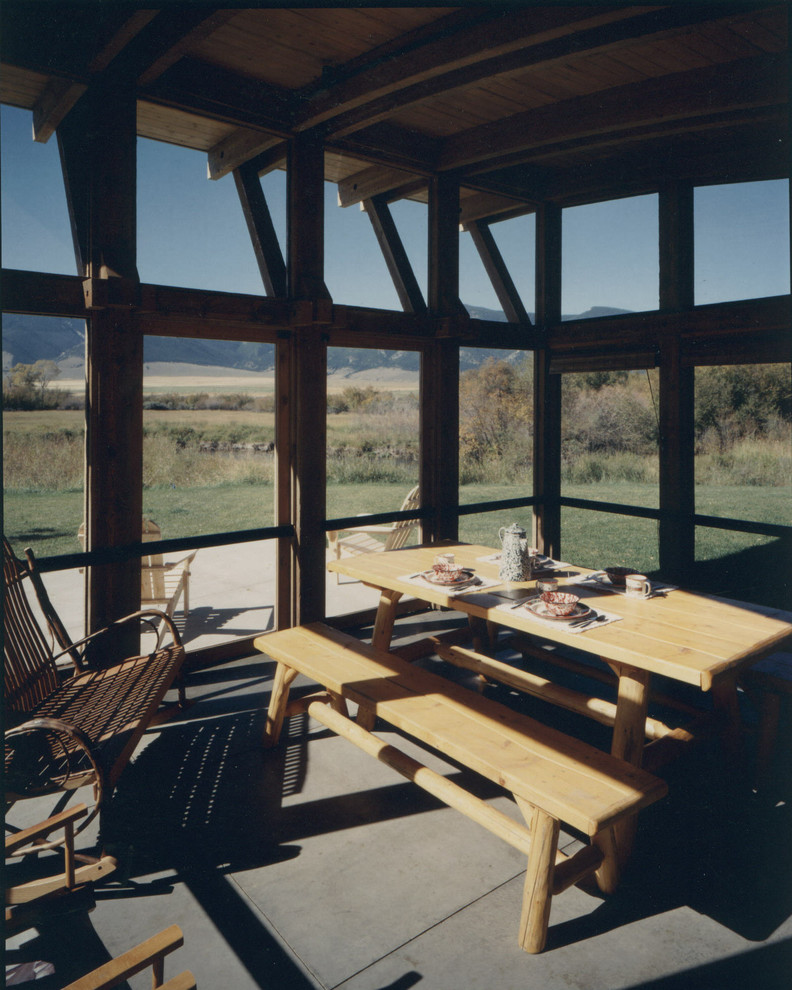 This is an example of a mid-sized rustic concrete paver back porch design.
