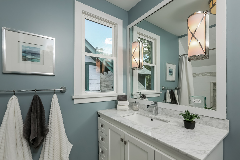 This is an example of a small arts and crafts master bathroom in Minneapolis with shaker cabinets, white cabinets, an alcove tub, a shower/bathtub combo, a two-piece toilet, white tile, ceramic tile, blue walls, marble floors, an undermount sink and marble benchtops.