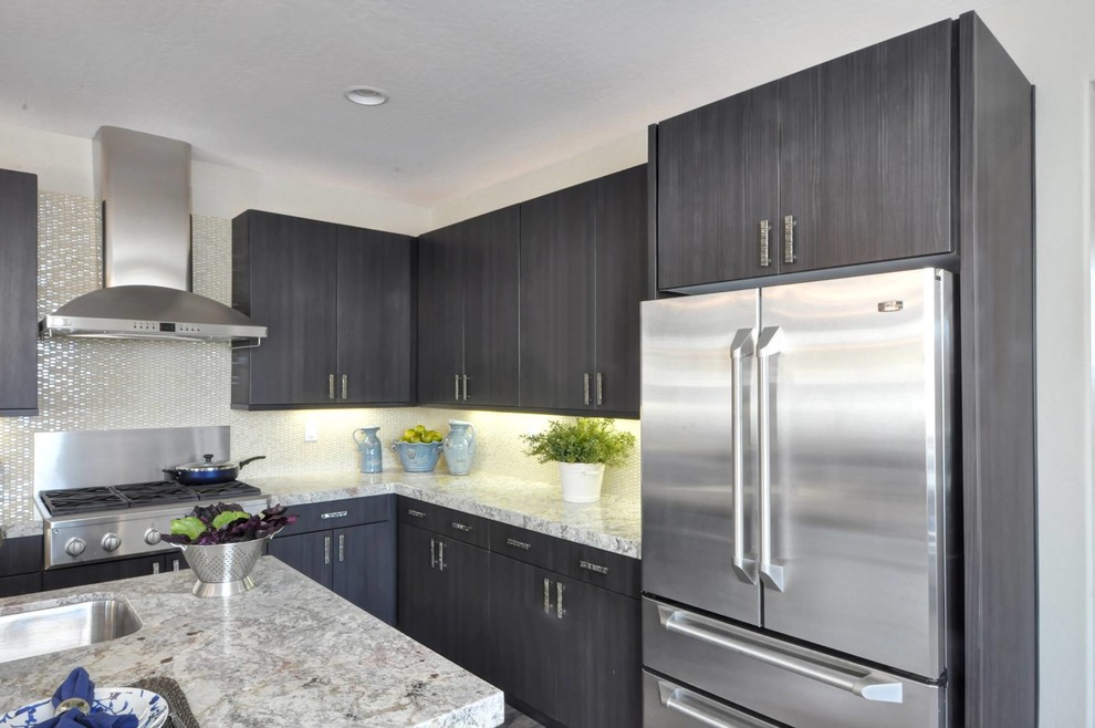 Example of a large transitional l-shaped medium tone wood floor kitchen pantry design in Phoenix with flat-panel cabinets, gray cabinets, white backsplash, glass tile backsplash, stainless steel appliances, an island, an undermount sink and granite countertops