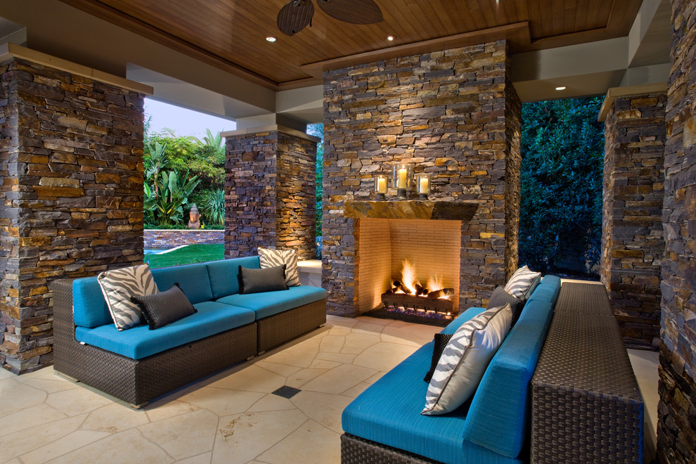 This is an example of a large contemporary backyard patio in Orange County with a fire feature, a roof extension and natural stone pavers.