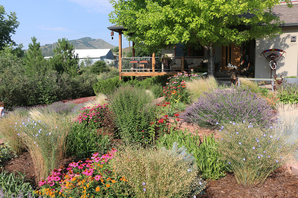 This is an example of a large front yard full sun xeriscape for summer in Denver with natural stone pavers.