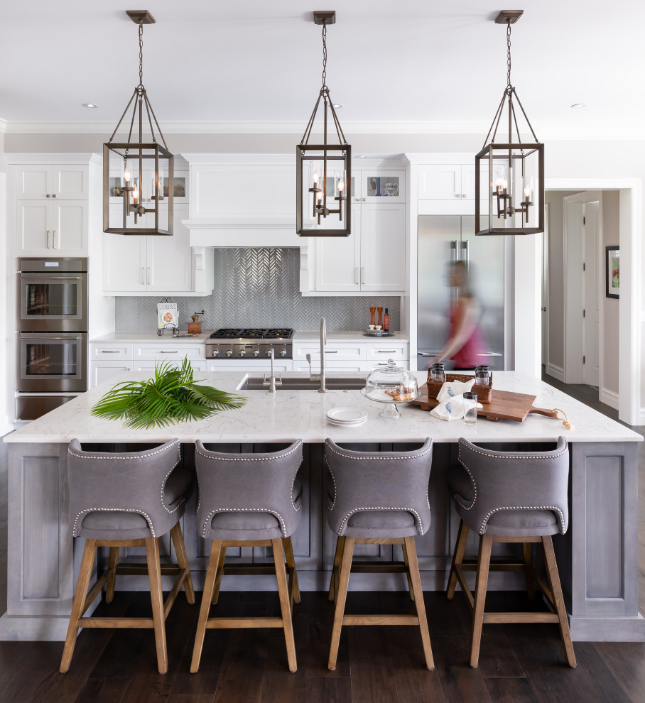 Inspiration for a beach style galley kitchen in Tampa with an undermount sink, shaker cabinets, white cabinets, grey splashback, mosaic tile splashback, stainless steel appliances, dark hardwood floors, with island, brown floor and white benchtop.