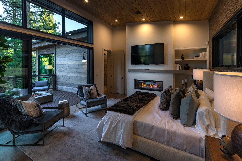 This is an example of a mid-sized modern master bedroom in Other with a standard fireplace, white walls, light hardwood floors, a stone fireplace surround and beige floor.